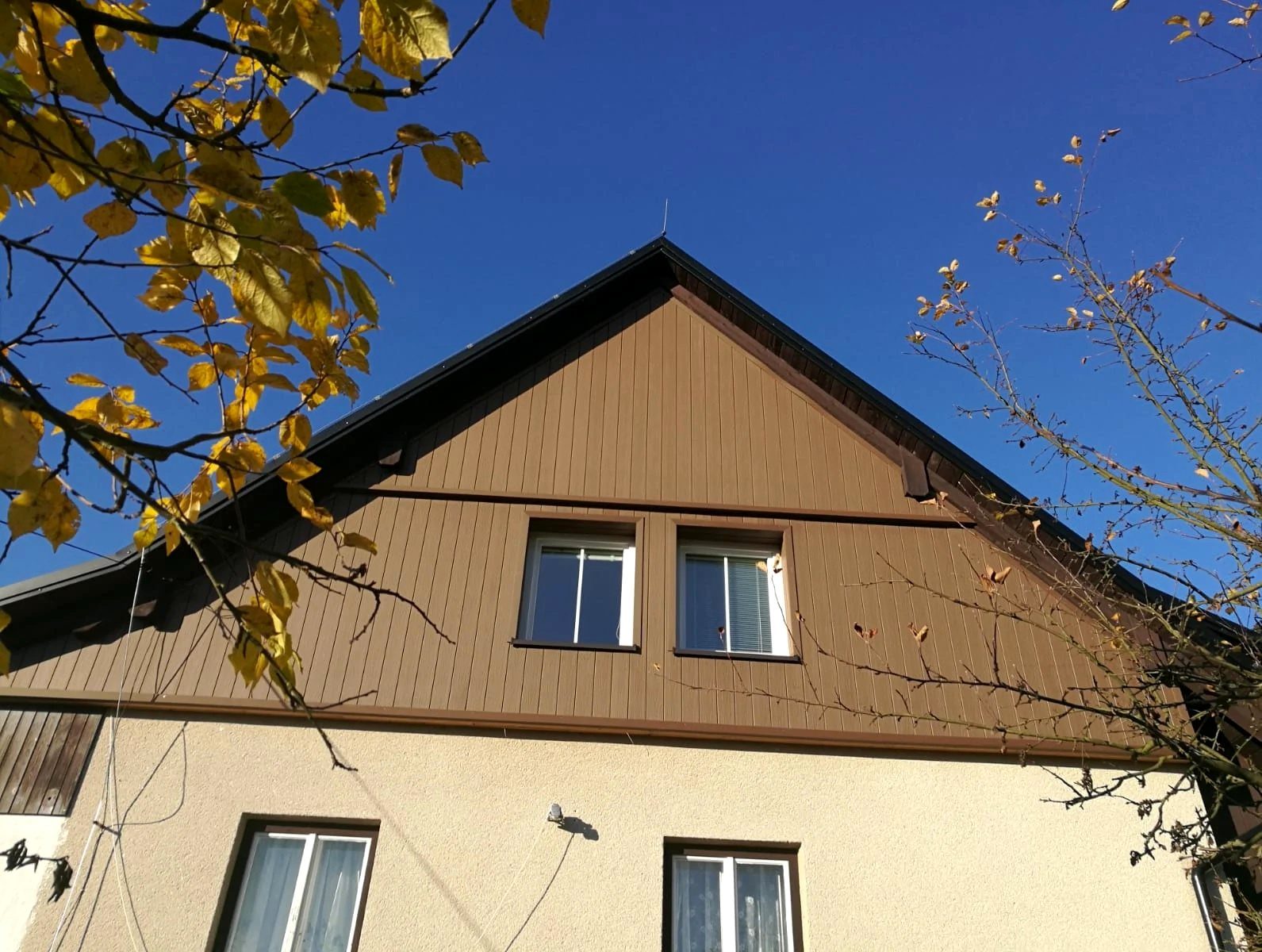Štít rodinného domu obložený hnědým WPC fasádním profilem